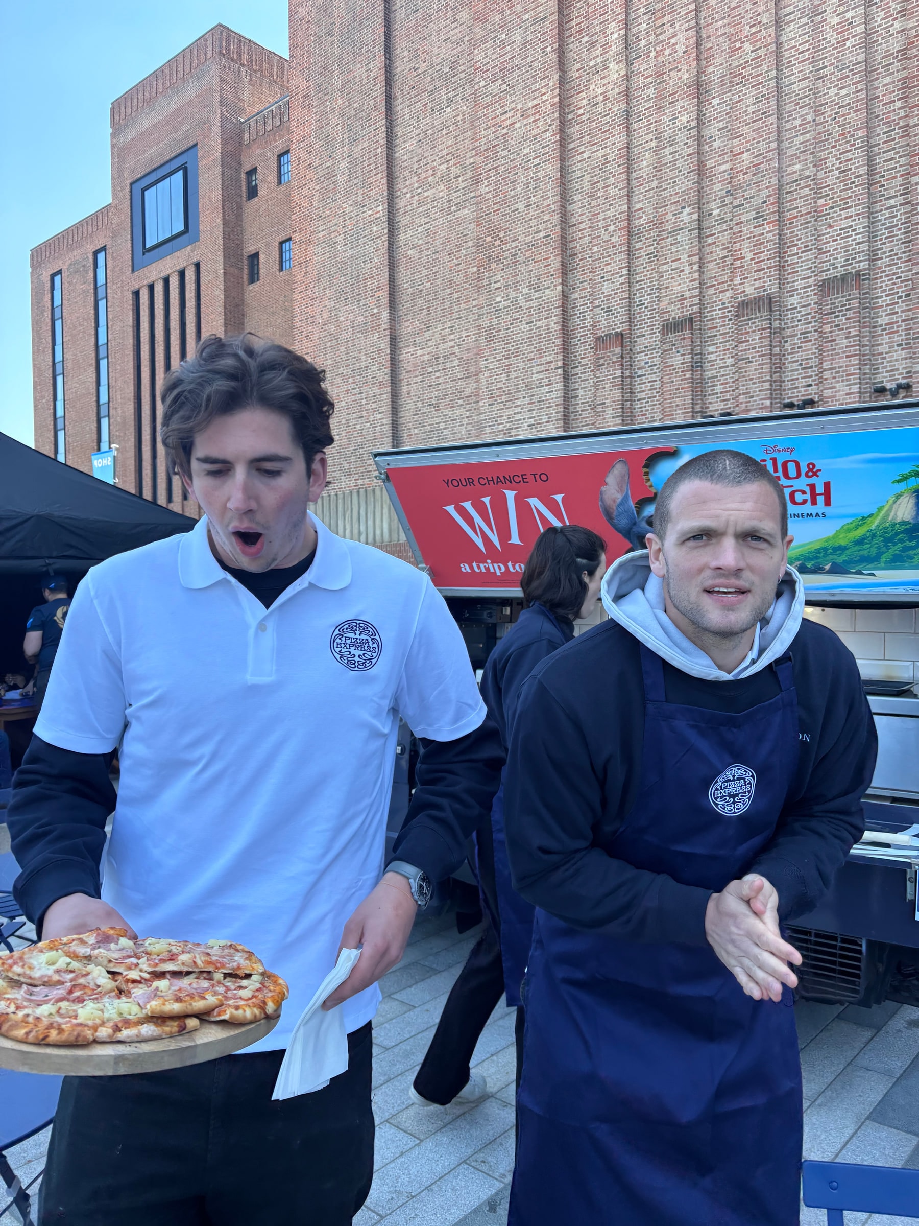 Louis carrying a tray of pizzas across an event floor