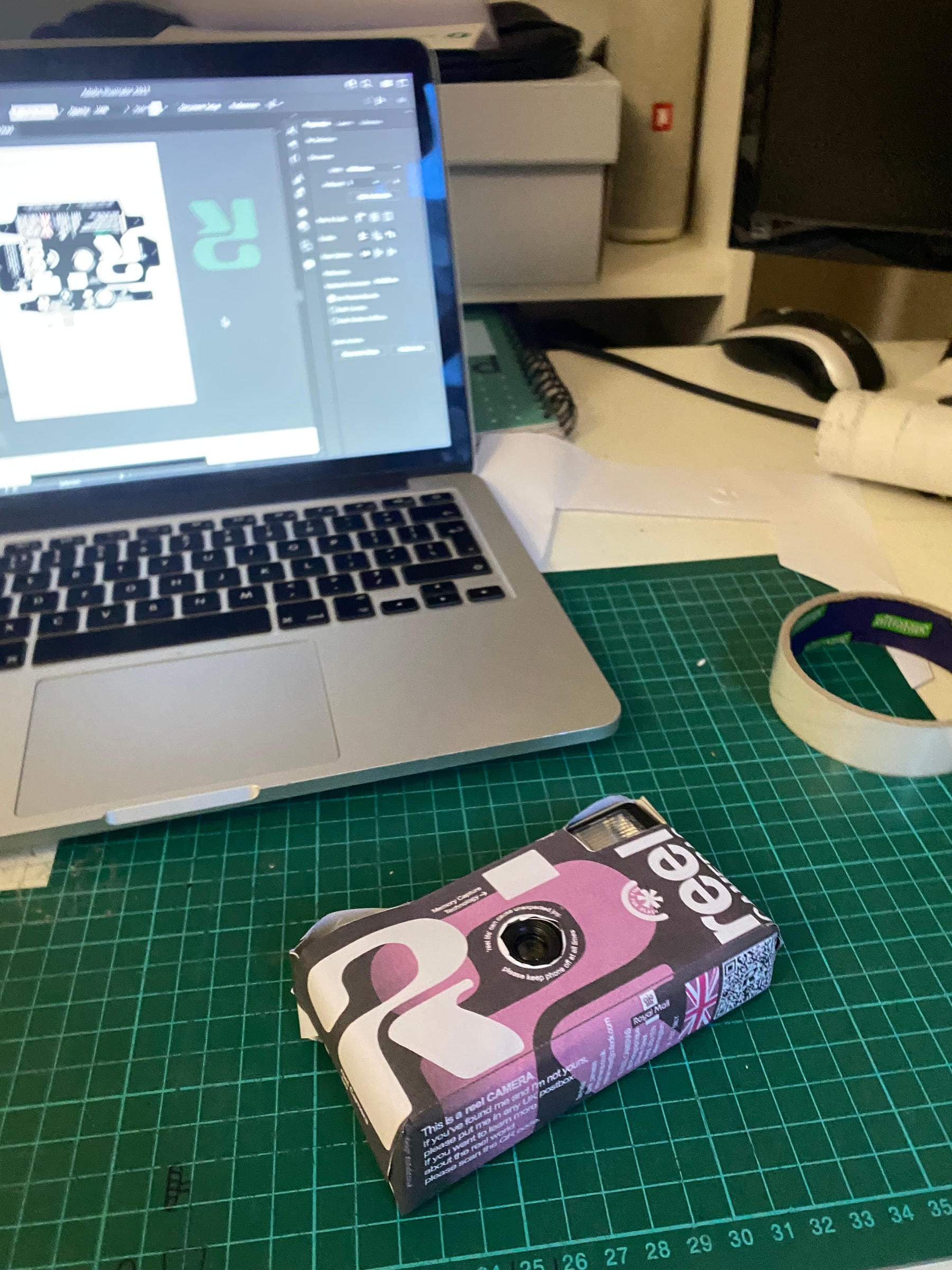 A paper prototype of the Reel camera beside the artwork open in Illustrator