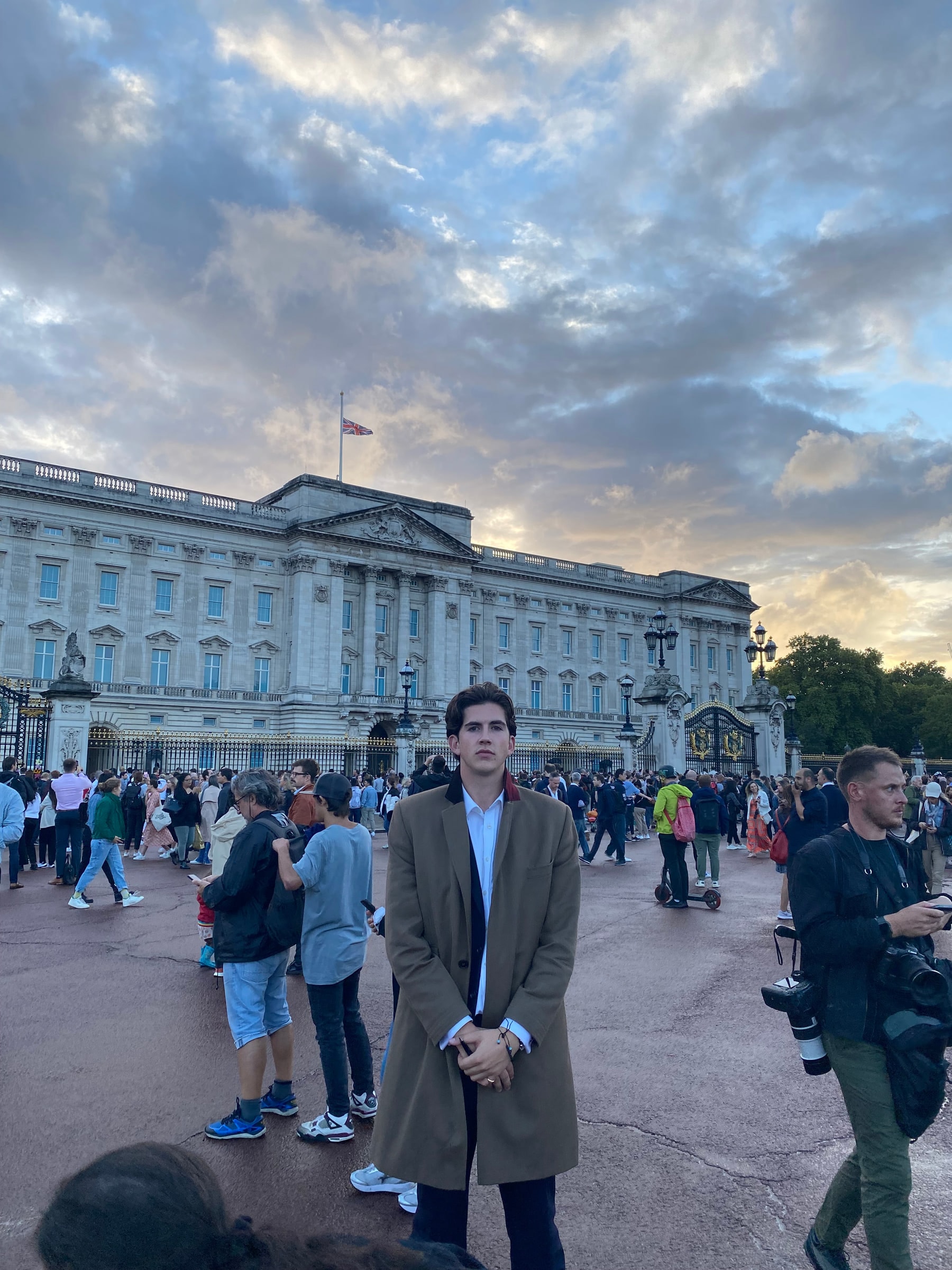Crowds outside Buckingham Palace with the flag at half mast at sunset