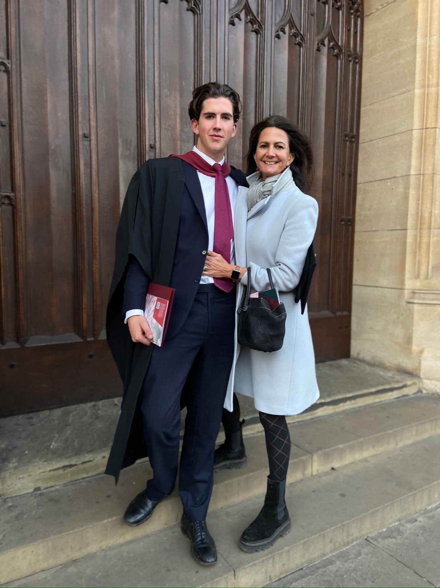 Louis in graduation gown standing with family on the steps