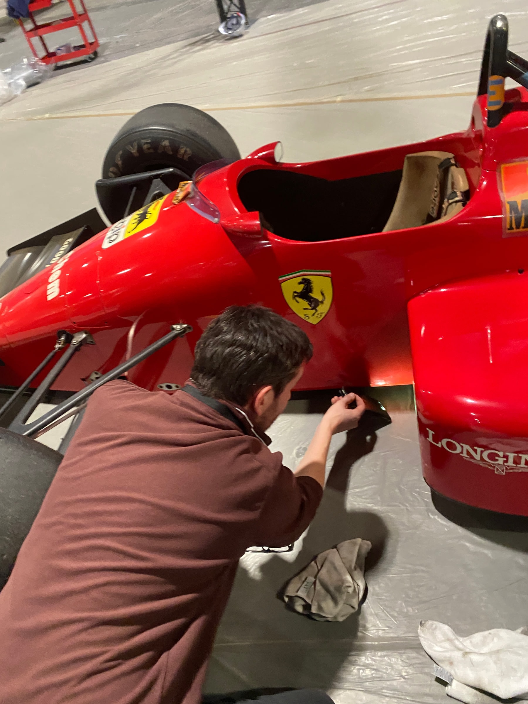 A technician polishing the flank of a red Ferrari Formula 1 car