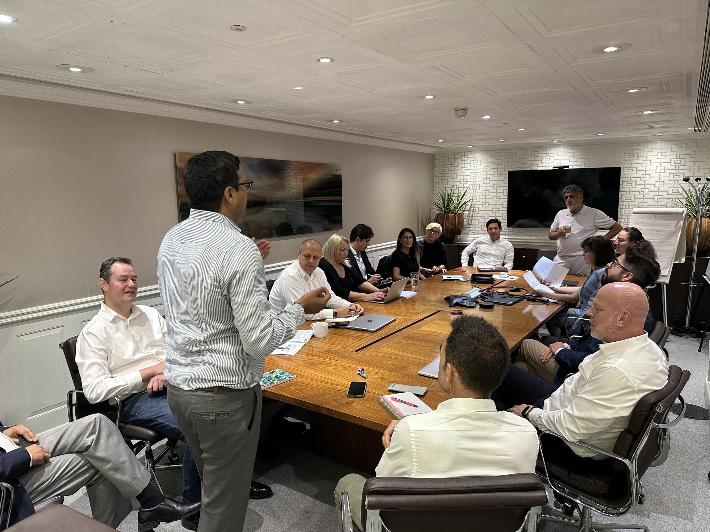 A boardroom meeting in progress around a long wooden table