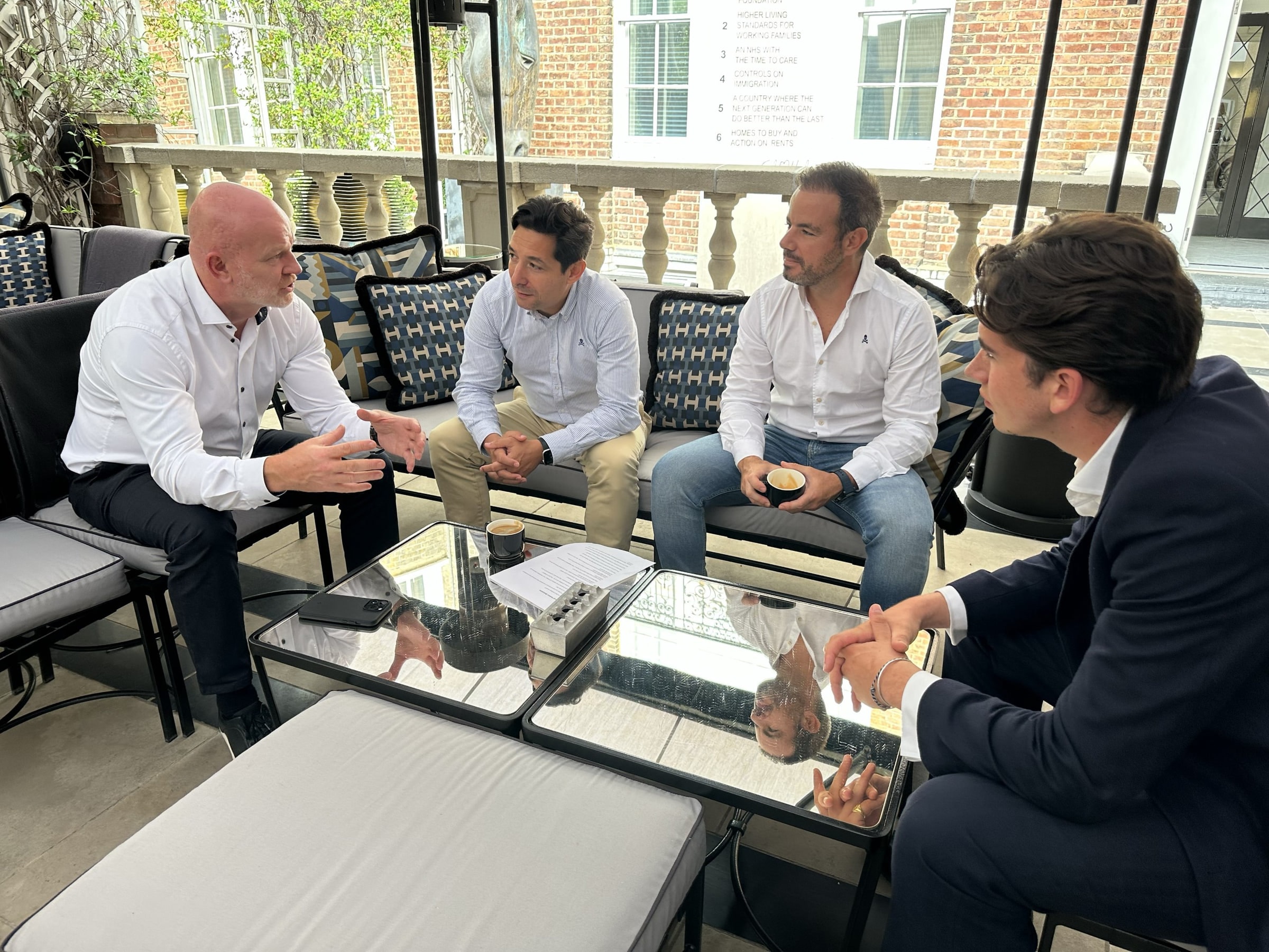 Four people in conversation around a low table on a Mayfair terrace