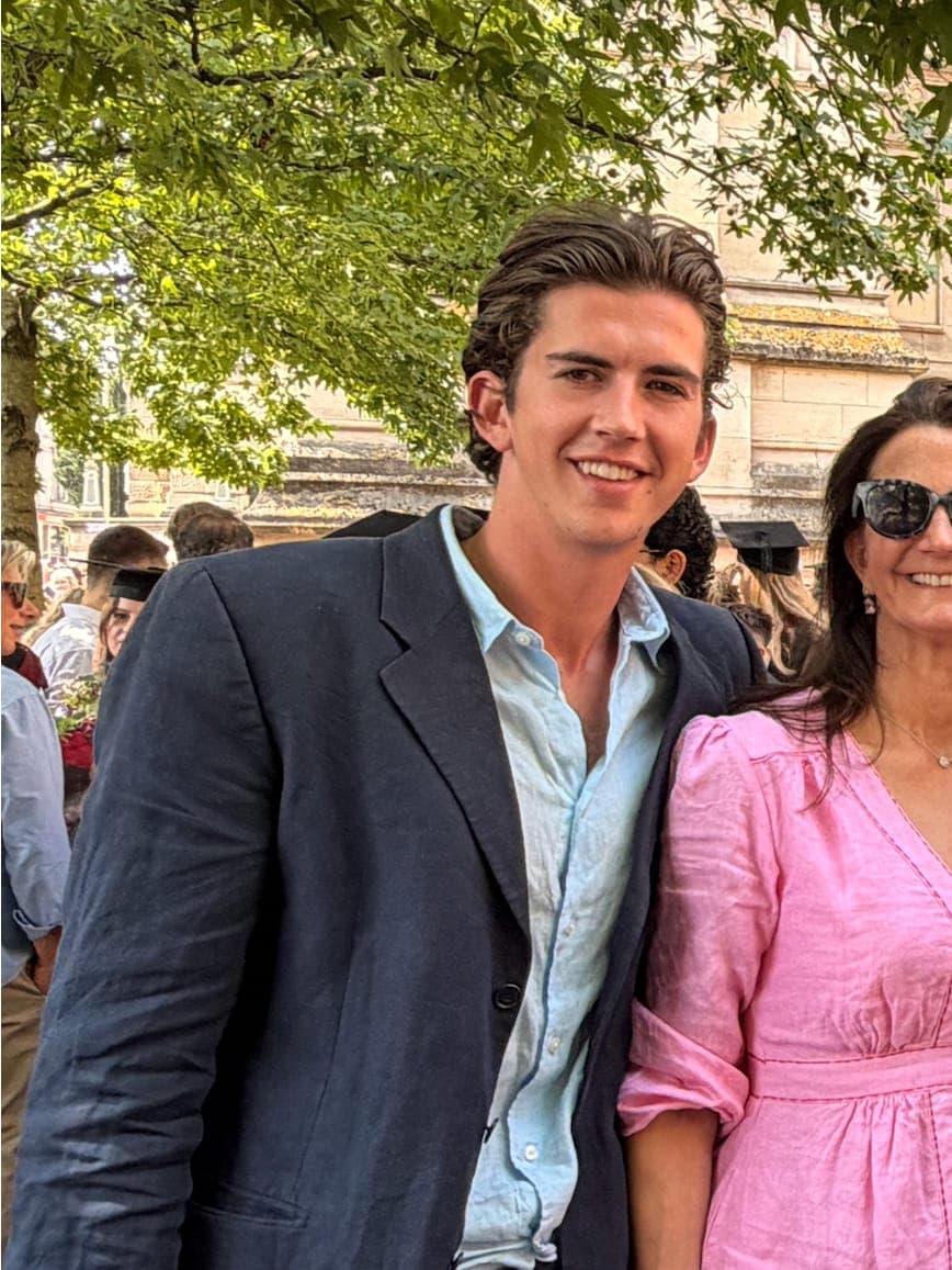 Louis outdoors in a navy linen jacket and open blue shirt, graduation day